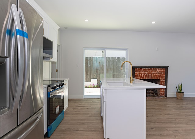 kitchen featuring plenty of natural light, light hardwood / wood-style floors, stainless steel appliances, and white cabinets