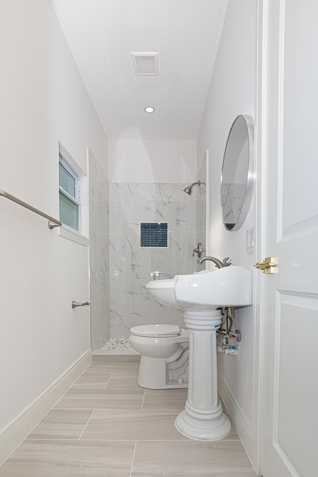 bathroom featuring tile flooring, a tile shower, and toilet