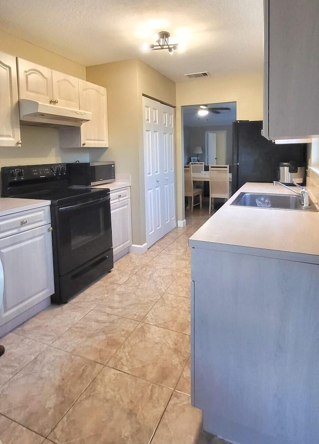 kitchen with white cabinetry, light tile floors, and black appliances