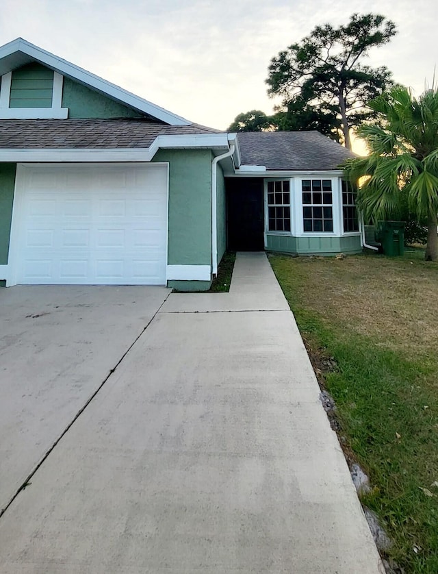 ranch-style home with a garage and a front lawn