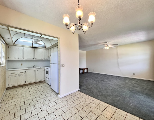 kitchen featuring white cabinetry, hanging light fixtures, light colored carpet, white appliances, and ceiling fan with notable chandelier