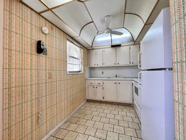 kitchen with sink, white cabinets, stove, and white refrigerator