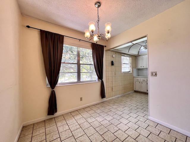 unfurnished room with a textured ceiling and a notable chandelier