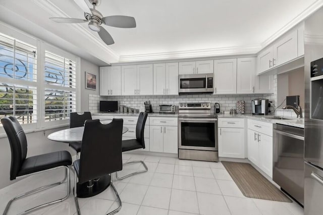 kitchen with appliances with stainless steel finishes, backsplash, ceiling fan, white cabinets, and light tile floors