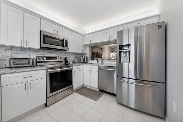 kitchen with light stone counters, light tile floors, backsplash, white cabinetry, and stainless steel appliances