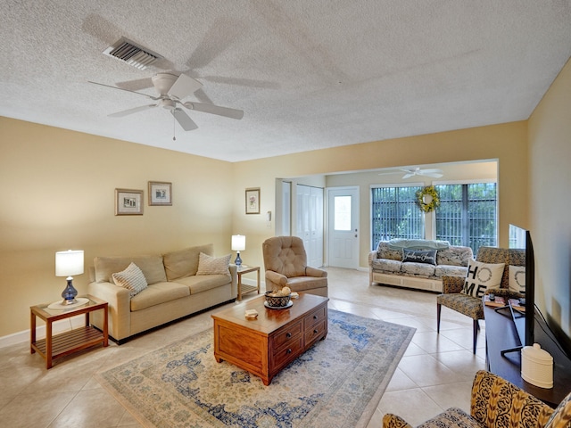 living room featuring a textured ceiling, ceiling fan with notable chandelier, and light tile patterned flooring