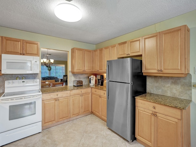 kitchen featuring light brown cabinetry, pendant lighting, and white appliances