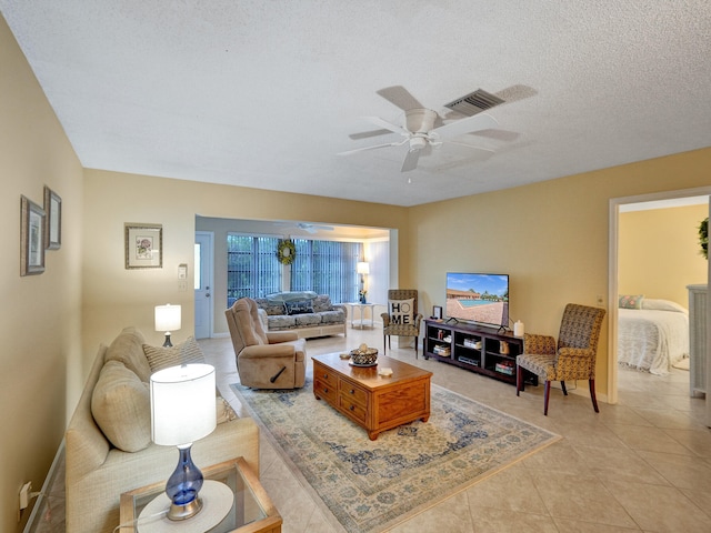 living room with ceiling fan with notable chandelier, light tile patterned floors, and a textured ceiling