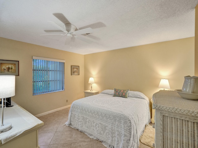 tiled bedroom with ceiling fan and a textured ceiling