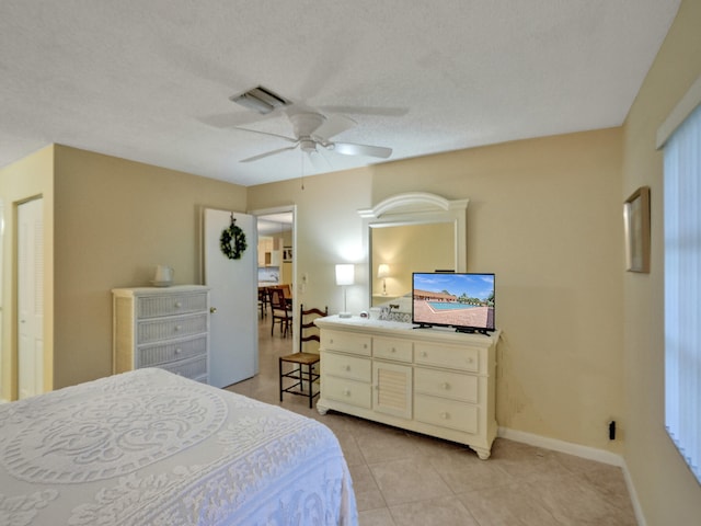 bedroom featuring ceiling fan, a closet, light tile patterned floors, and a textured ceiling