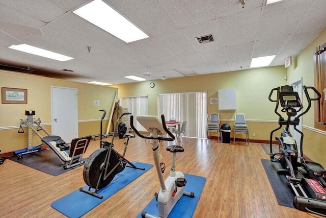 exercise area featuring a paneled ceiling and light hardwood / wood-style floors