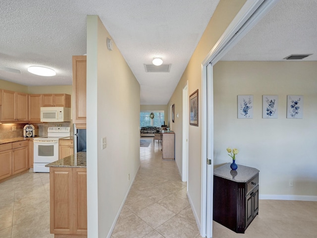 hall with a textured ceiling and light tile patterned flooring