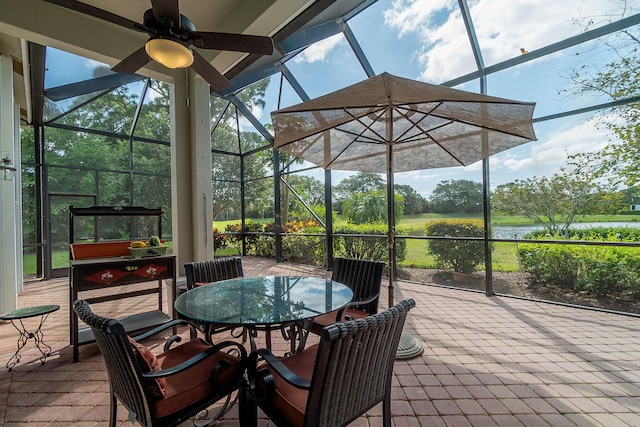 view of patio with ceiling fan, a water view, and glass enclosure