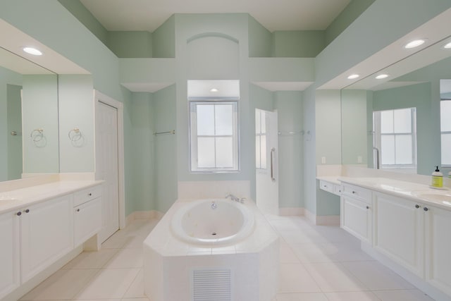 bathroom with tiled tub, vanity, and tile patterned floors