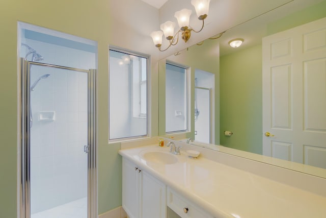 bathroom with a shower with door, vanity, and an inviting chandelier