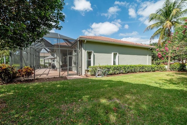 rear view of property with a yard, a patio, and glass enclosure