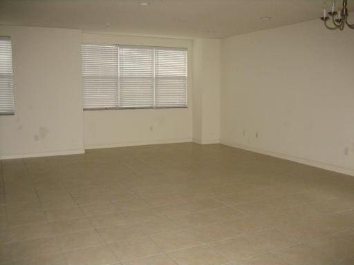 spare room with a chandelier and light tile floors