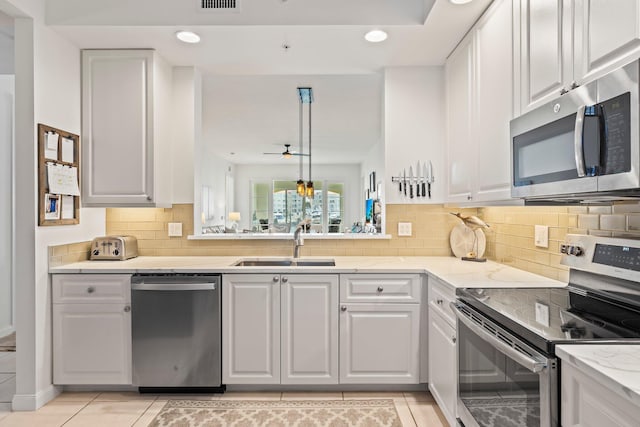 kitchen with white cabinetry, appliances with stainless steel finishes, sink, and hanging light fixtures