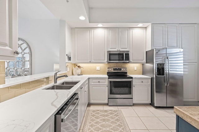 kitchen featuring sink, stainless steel appliances, tasteful backsplash, light stone countertops, and light tile patterned flooring