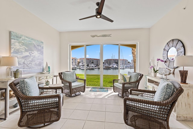 living area featuring light tile patterned flooring, ceiling fan, and a water view