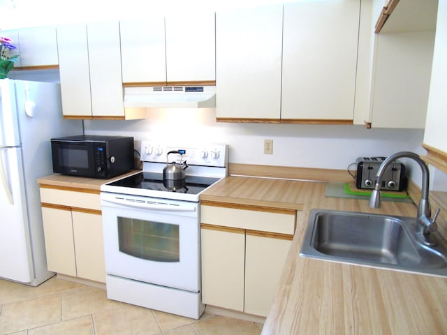 kitchen with white appliances, light countertops, under cabinet range hood, a sink, and light tile patterned flooring