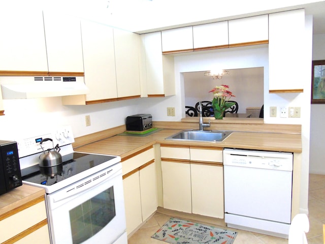 kitchen with light tile patterned floors, white appliances, light countertops, under cabinet range hood, and a sink