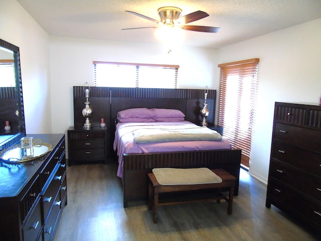 bedroom with ceiling fan, a textured ceiling, and dark hardwood / wood-style flooring