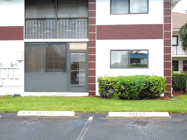 view of exterior entry with uncovered parking and stucco siding