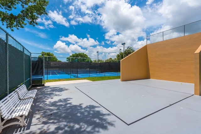 surrounding community featuring a tennis court and fence