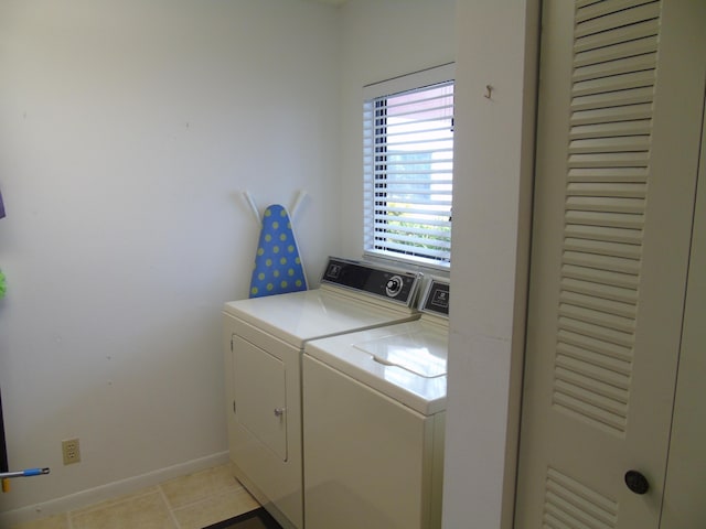 clothes washing area with laundry area, washing machine and dryer, light tile patterned floors, and baseboards