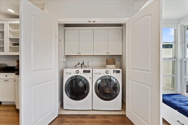 clothes washing area with cabinets, washer hookup, wood-type flooring, and separate washer and dryer