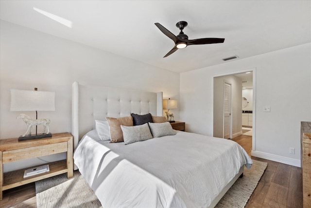 bedroom featuring ceiling fan, ensuite bath, and dark hardwood / wood-style floors