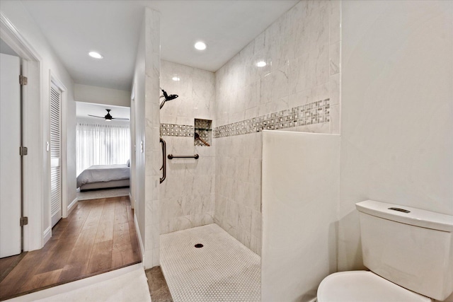 bathroom with toilet, ceiling fan, hardwood / wood-style floors, and a tile shower