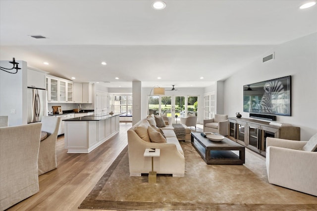 living room with sink, light hardwood / wood-style flooring, and ceiling fan