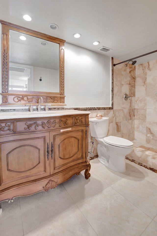 bathroom with vanity, toilet, tile walls, and a tile shower