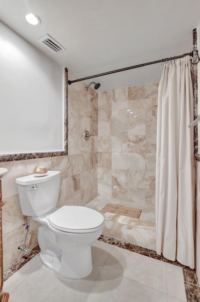 bathroom with tile walls, a shower with curtain, tile patterned floors, and toilet