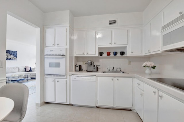 kitchen featuring sink, white cabinetry, tasteful backsplash, light tile patterned floors, and white appliances