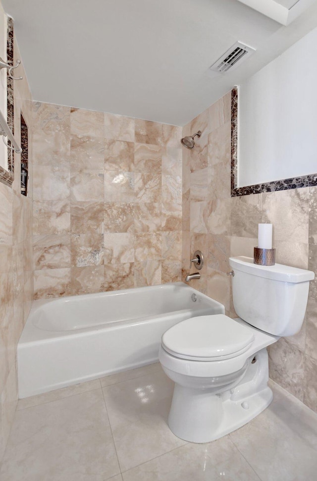 bathroom featuring tile walls, tiled shower / bath, tile patterned floors, and toilet