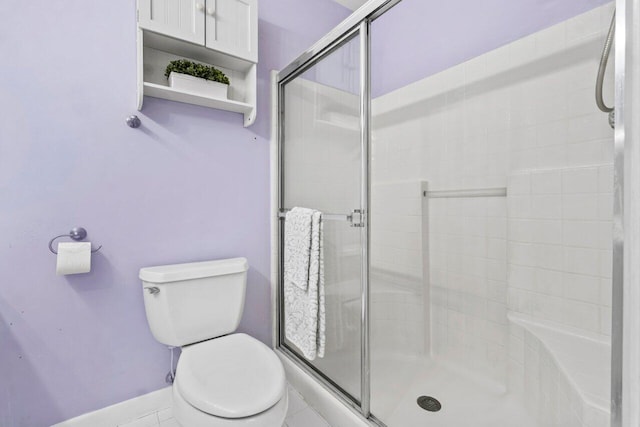 bathroom featuring a shower with shower door, tile patterned floors, and toilet