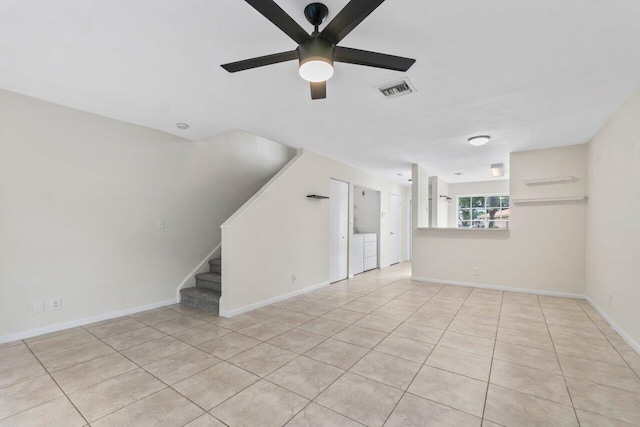 unfurnished living room featuring light tile patterned flooring, ceiling fan, and washing machine and dryer