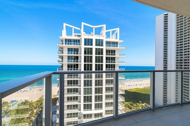 balcony with a water view and a view of the beach