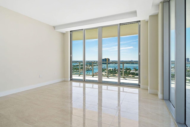 tiled empty room featuring a wall of windows and a water view