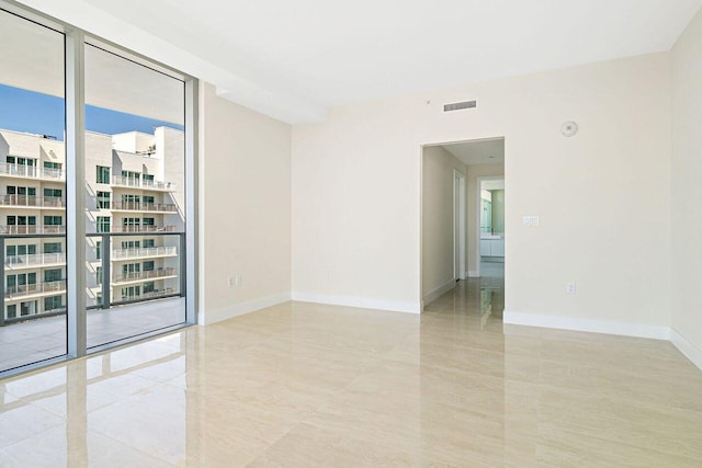 unfurnished room with a wall of windows, light tile floors, and a wealth of natural light