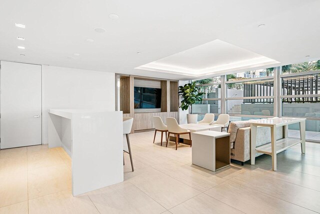 living room featuring expansive windows, a raised ceiling, and light tile floors