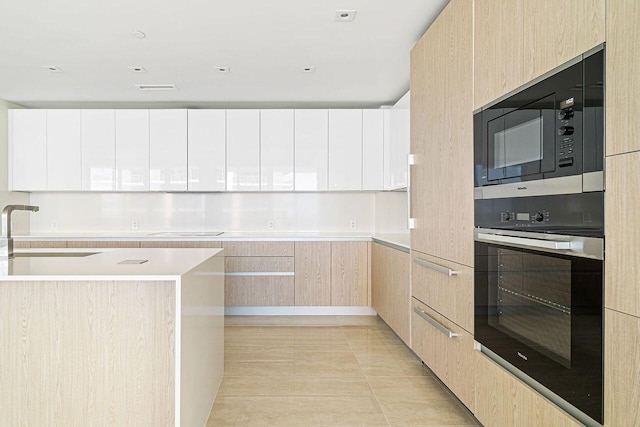 kitchen with light brown cabinets, white cabinets, sink, light tile flooring, and black appliances