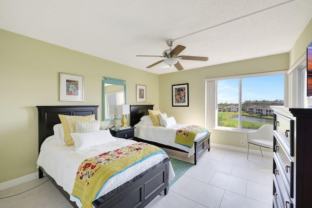 bedroom with baseboards, a textured ceiling, light tile patterned flooring, and a ceiling fan