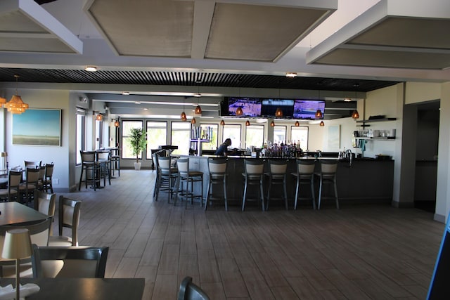 bar with a community bar and wood finished floors