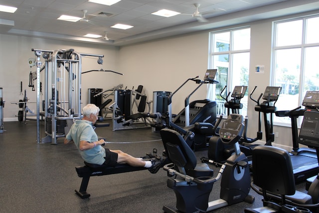 workout area with visible vents, a paneled ceiling, and baseboards