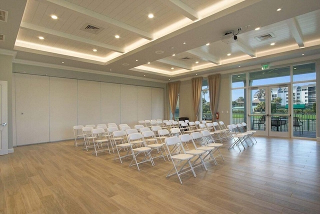 cinema with beam ceiling, light wood-type flooring, and french doors