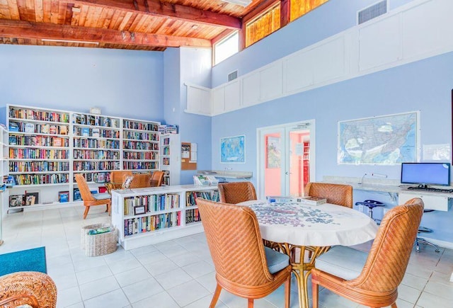 tiled dining room featuring beam ceiling, wooden ceiling, and a high ceiling